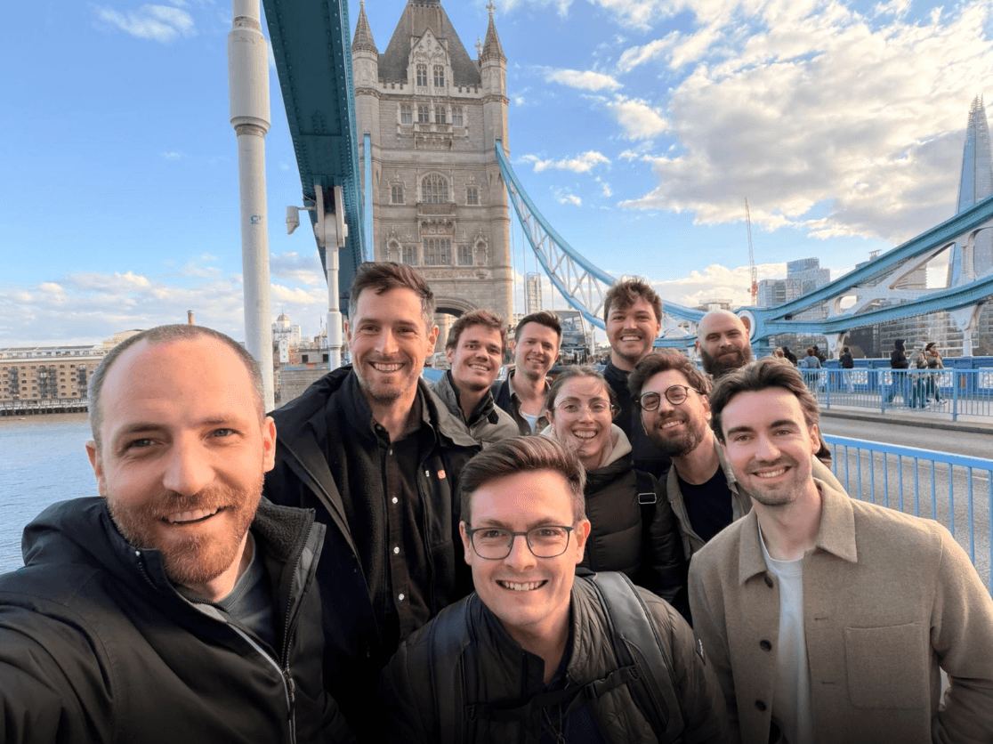 A group selfie in front of Tower Bridge in London on a bright day.