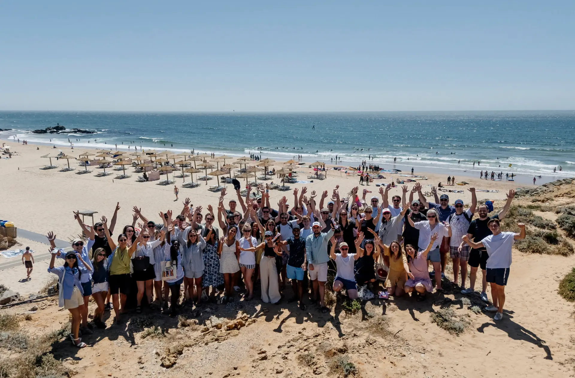 The Conveo team gathered on a beach, arms raised for a group photo.